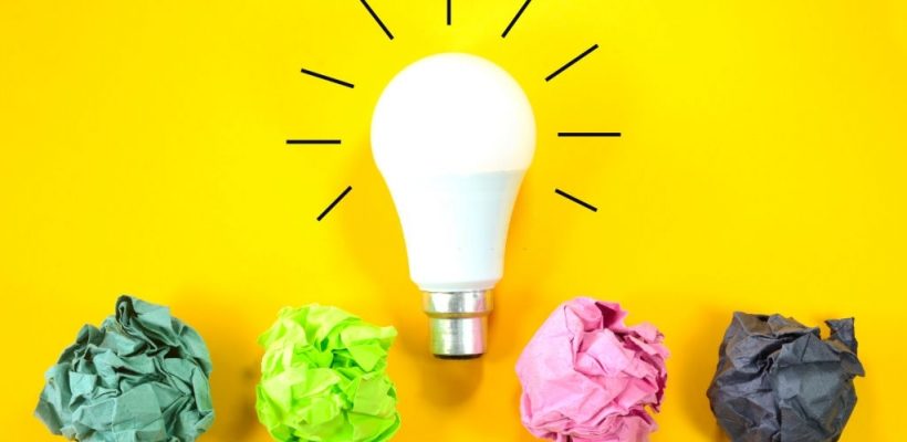Concept of Creative Ideas and Innovation. Bulb glowing with crumpled paper balls on a yellow background.